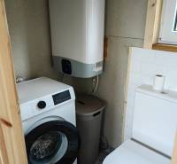 Tiny house - malý domček - Kúpeľňa v rodinnom dome s práčkou, bojlerom a toaletou. Podlaha má dekoratívne obklady.