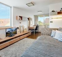 Predaj moderná 5 izbová vila, 265 m2, pozemok 953 m2, bazén,BA II. - Interiér izby na ulici Imelová s pohovkou, stolíkom a písacím stolom vedľa okna.