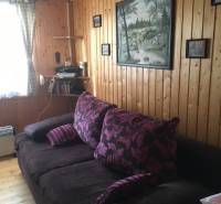 Záhrada na predaj – Kráľová nad Váhom 29 900 € - Dohoda Možná - Drevenými panelmi obložená stena s pohovkou, obrazom a poličkou v chate.