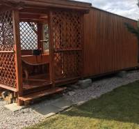 Záhrada na predaj – Kráľová nad Váhom 29 900 € - Dohoda Možná - Drevená chata v Kráľovej nad Váhom s malou vyvýšenou terasou a trávnikom.