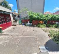 Výborný rodinný dom pre pohodlné bývanie - Rodinný dom v Tachtoch s dvorom, betónovou plochou, zeleňou, plotom a garážovými dverami.