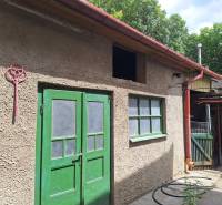 Výborný rodinný dom pre pohodlné bývanie - Rodinný dom v Tachtoch s dvoma zelenými dverami a svetloodtenkovou fasádou.