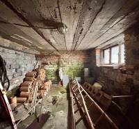 Predaj rodinného domu v Skalitom  - Suterén rodinného domu s tehlovými stenami a stropom, uskladnené rúry a náradie.