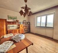 Predaj rodinného domu v Skalitom  - Izba v rodinnom dome s dreveným dekorom, vintage nábytkom, lustrom a veľkým oknom.