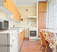 PRÍJEMNÝ 3 IZBOVÝ BYT | BOŠANY  - Kuchyňa v 3-izbovom byte so spotrebičmi, drevené skrinky, stôl, kachličkový obklad.