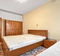 PRÍJEMNÝ 3 IZBOVÝ BYT | BOŠANY  - Spálňa so svetlými stenami a dreveným nábytkom v 3-izbovom byte.