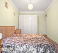 PRÍJEMNÝ 3 IZBOVÝ BYT | BOŠANY  - Spálňa v 3-izbovom byte s posteľou, šatníkom a lampou. Podlaha s dreveným dekorom.