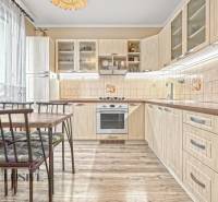 PRÍJEMNÝ 3 IZBOVÝ BYT | P.O.HVIEZDOSLAVA | TOPOĽČANY - Kuchyňa v 3-izbovom byte s podlahou s dreveným dekorom, svetlým nábytkom a jedálenským stolom.