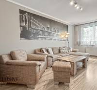 PRÍJEMNÝ 3 IZBOVÝ BYT | P.O.HVIEZDOSLAVA | TOPOĽČANY - Útulná obývačka so sedačkou, stolíkom a podlahou s dreveným dekorom v 3-izbovom byte.