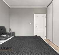 PRÍJEMNÝ 3 IZBOVÝ BYT | P.O.HVIEZDOSLAVA | TOPOĽČANY - Spálňa v 3-izbovom byte s tmavým čelom postele, sivými stenami a skriňou.