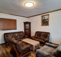 Investujte do budúcnosti - Obývačka v rodinnom dome s koženými sedacími súpravami a podlahou s dreveným dekorom.