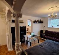 Investujte do budúcnosti - Obývačka v rodinnom dome s pohovkou, sklom stolom a stĺpmi.