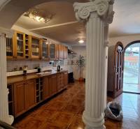 Investujte do budúcnosti - Interiér rodinného domu s drevenou kuchynskou linkou, stĺpmi a podlahou s dreveným dekorom.