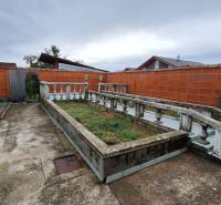 Investujte do budúcnosti - Dvor rodinného domu v Zacharovciach s kvetinovým záhonom a betónovým chodníkom.