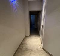 NOVINKA .... Na  predaj 3 izbový byt na sídlisku SNP v Michalovciach - Chodba s podlahou s dreveným dekorom, osvetlením a bielymi stenami v 3-izbovom byte.