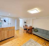 *PRENÁJOM* bezbariérový 1 izbový byt Lesná / Banka - Obývacia časť 1-izbového bytu s pohovkou, jedálenský stôl, kuchyňa a podlaha s dreveným dekorom.