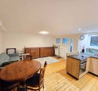 *PRENÁJOM* bezbariérový 1 izbový byt Lesná / Banka - Obývacia izba v 1-izbovom byte s podlahou s dreveným dekorom, sedačkou a jedálenským stolom.