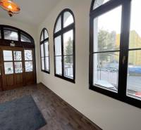 PREŠOV-ŠIRŠIE CENTRUM,POLYFUNKČNÁ BUDOVA,VL.PARKOVISKO,UL.VAJANSKÉHO - Budova s podlahou s dreveným dekorom a veľkými oknami na Vajanského ulici v Prešove.