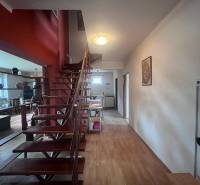 PRIESTRANNÝ 7-IZBOVÝ RODINNÝ DOM S VEĽKÝM POZEMKOM V DLHEJ NAD VÁHOM  - Interiér rodinného domu s drevenými schodmi a podlahou s dreveným dekorom.