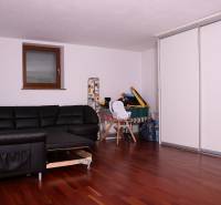 Na predaj rodinný dom na Súľovskej 56 v Bratislave - Rodinný dom s čiernou sedačkou, bielymi skriňami a podlahou s dreveným dekorom.