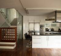 Na predaj rodinný dom na Súľovskej 56 v Bratislave - Kuchyňa v rodinnom dome s podlahou s dreveným dekorom a skleneným zábradlím schodiska.