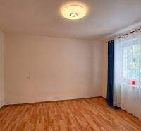 Rodinný dom po čiastočnej rekonštrukcii - Izba v rodinnom dome s podlahou s dreveným dekorom a závesmi pri okne.