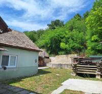 Rodinný dom po čiastočnej rekonštrukcii - Rodinný dom v Hajnáčke s dvorom, drevárňou a zelenými stromami na okolí.