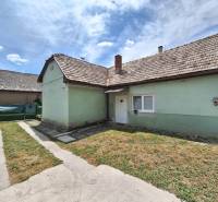 Rodinný dom po čiastočnej rekonštrukcii - Rodinný dom v Hajnáčke s asfaltovým chodníkom a zeleným trávnikom pod modrou oblohou.