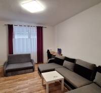 Rodinný dom po čiastočnej rekonštrukcii - Obývačka v rodinnom dome s rohovou sedačkou a podlahou s dreveným dekorom.