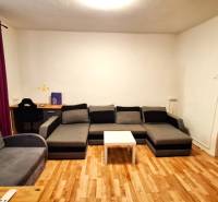 Rodinný dom po čiastočnej rekonštrukcii - Obývacia izba v rodinnom dome s podlahou s dreveným dekorom a šedým nábytkom.