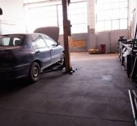 Prevádzková budova-AUTOSERVIS na predaj vo Veľkých Úľanoch - Auto na zdviháku v interiéri výrobných priestorov s veľkými oknami.