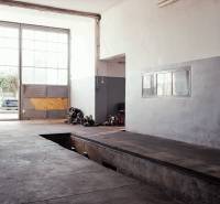 Prevádzková budova-AUTOSERVIS na predaj vo Veľkých Úľanoch - Výrobné priestory s veľkými oknami, garážovou bránou a podlahou s dreveným dekorom.