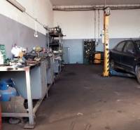 Prevádzková budova-AUTOSERVIS na predaj vo Veľkých Úľanoch - V dielni sú náradia, auto na zdviháku a roztrúsené diely na podlahe.