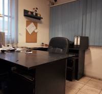 Prevádzková budova-AUTOSERVIS na predaj vo Veľkých Úľanoch - Kancelária s tmavým stolom, dlažbou a modrými vertikálnymi žalúziami vo výrobných priestoroch.