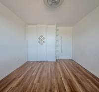 REZERVOVANÝ! Nová cena! Moderný 2-izbový byt – Galanta, sídlisko West - Izba s podlahou s dreveným dekorom, vstavanou skriňou a poličkami v 2-izbovom byte.