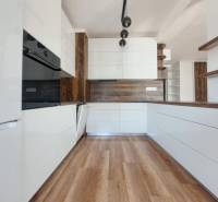 REZERVOVANÝ! Nová cena! Moderný 2-izbový byt – Galanta, sídlisko West - Kuchyňa v 2-izbovom byte s bielymi skrinkami a podlahou s dreveným dekorom.