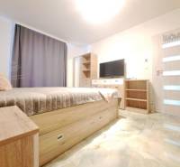 Neodolateľná ponuka! 4-izbová novostavba Galanta-Kolónia za super cenu - Spálňa v rodinnom dome s posteľou, šatníkovou skriňou, televízorom a podlahou s dreveným dekorom.