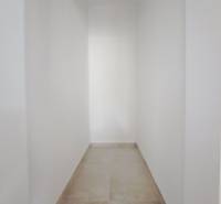 Priestranné novostavby 4-izbových rodinných domov v meste Šaľa - Úzky chodba v rodinnom dome s bielymi stenami a svetlou podlahou.