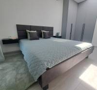 SKOLAUDOVANÉ! Novostavba 2-3 izbových bytov s pozemkom Richtárske pole - Spálňa s veľkou posteľou, sivými skriňami a čiernym lustrom v 2-izbovom byte.