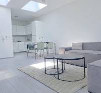 SKOLAUDOVANÉ! Novostavba 2-3 izbových bytov s pozemkom Richtárske pole - Svetlá obývačka s kuchyňou, pohovkou a podlahou s dreveným dekorom v 2-izbovom byte.