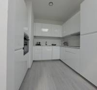 SKOLAUDOVANÉ! Novostavba 2-3 izbových bytov s pozemkom Richtárske pole - Moderná kuchyňa s bielymi skrinkami a podlahou s dreveným dekorom v 2-izbovom byte.