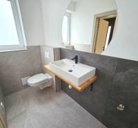 VEĽKORYSO RIEŠENÝ 4 izbový RD-128 m2 S TEP. ČERPADLOM, POZEMOK 405 m2 - Kúpeľňa v rodinnom dome s umývadlom, oknom a obkladmi v sivých odtieňoch.