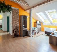 Kúpte si veľký PODKROVNÝ 4i BYT so ZÁHRADOU a PIVNICOU v Starom meste - Podkrovný interiér 4-izbového bytu s drevenou podlahou, knihovňou a svetlými stenami.