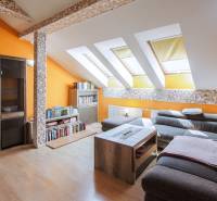 Kúpte si veľký PODKROVNÝ 4i BYT so ZÁHRADOU a PIVNICOU v Starom meste - Podkrovná obývacia izba v 4-izbovom byte s oranžovými stenami a sedačkou.