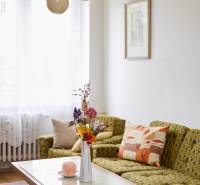 NA PREDAJ,3-IZBOVÝ TEHLOVÝ BYT,KOŠICE-ŠACA - Svetlá obývačka v 3-izbovom byte s pohovkou, stolom a dekoratívnymi kvetmi v váze.