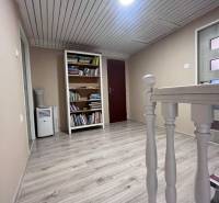 Dvojpodlažný 5i RD pri Dunajskej Strede, 55 min od BA - Chodba s podlahou s dreveným dekorom, knižnicou a svetlým dreveným zábradlím v rodinnom dome.