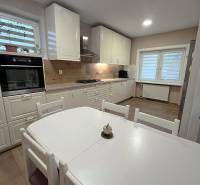 Dvojpodlažný 5i RD pri Dunajskej Strede, 55 min od BA - Kuchyňa v rodinnom dome s bielym nábytkom a podlahou s dreveným dekorom.