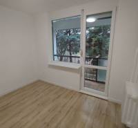  Na predaj  3i byt s vlastnou garážou neďaleko Šale - Izba so svetlými stenami, podlahou s dreveným dekorom a výhľadom na zeleň.