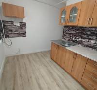  Na predaj  3i byt s vlastnou garážou neďaleko Šale - Kuchyňa v 3-izbovom byte má drevený dekor podlahy a jednoduché skrinky.