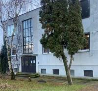  Na predaj  3i byt s vlastnou garážou neďaleko Šale - Exteriér budovy v Seliciach, obklopený stromami a trávnatým prostredím.